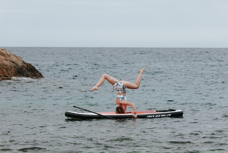 postura de yoga en tabla paddle surf